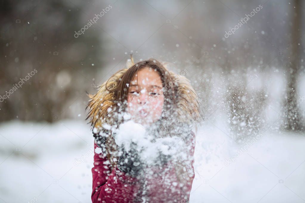 Emotions child girl plays with snow outdoor at winter.