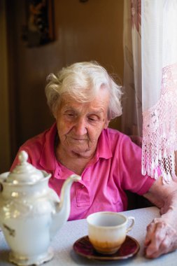 Yaşlı büyükanne evinde çay içer.