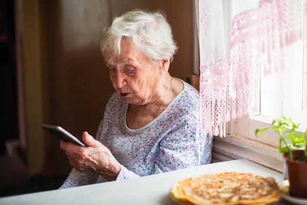 老妇人手里拿着智能手机坐着 — 图库照片