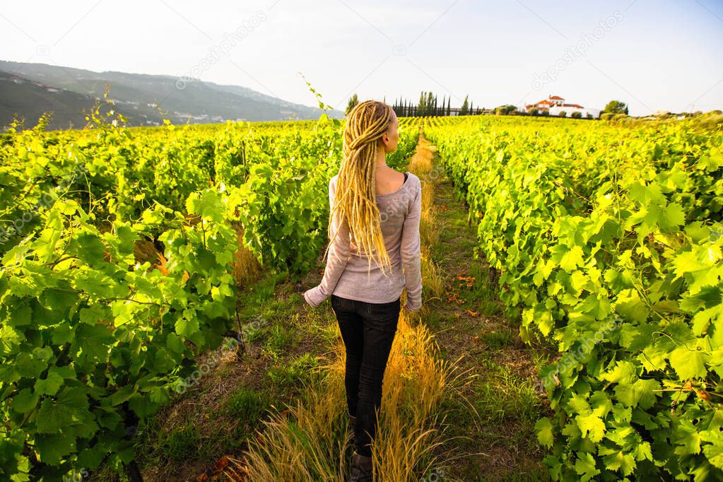 Woman with blond dreadlocks in the vineyards. 