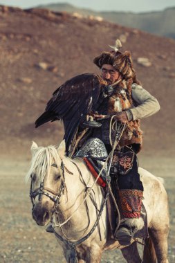 Sagsay, Moğolistan - 28 Eylül 2017: Berkutchi (kazak kartal Hunter) ise bir altın kartallar ile tavşan Bayan-Olgii Aymağı dağlarında kolları üzerinde avcılık. 
