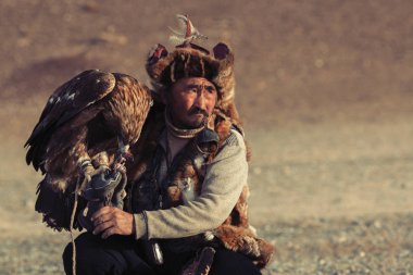 Sagsay, Moğolistan - 28 Eylül 2017: Berkutchi (kazak kartal Hunter) ise bir altın kartallar ile tavşan Bayan-Olgii Aymağı dağlarında kolları üzerinde avcılık. 