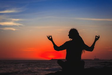 gün batımında sahilde Yoga uygulamak siluet genç kadın.