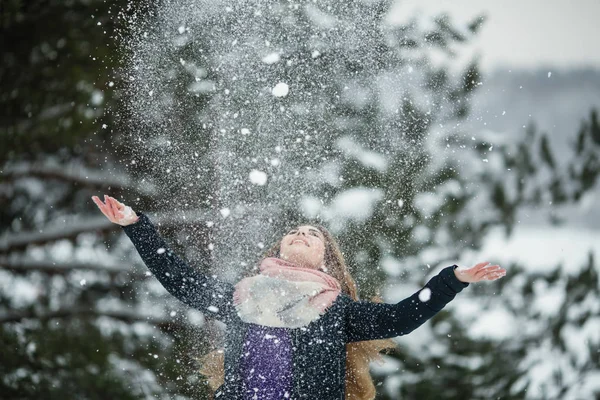 Funny girl playing with snow in an amazing winter\'s park.