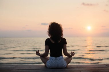 Yoga siluet. Meditasyon kız günbatımı sırasında denizde. 