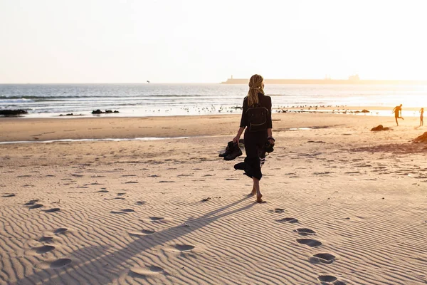若い女性は 夕暮れ時 海の砂浜のビーチに沿って歩く — ストック写真