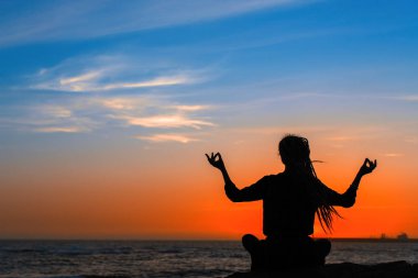 Yoga kadın silueti şaşırtıcı kırmızı günbatımı sırasında okyanus üzerinde.