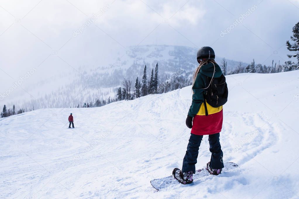 Woman snowboarder freerider with snowboard in the mountains on a snowy slope.