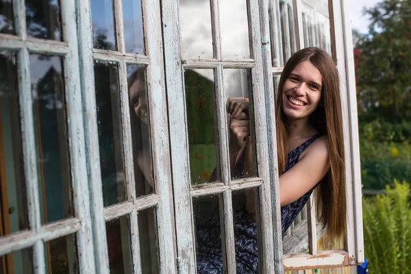 Uzun Saçlı Genç Kadın Verandanın Penceresinden Bakıyor — Stok fotoğraf
