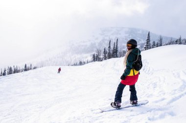 Snowboard karlı bir yamaç dağlarda kızla.