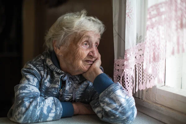 Elderly Woman Looks Out Window — Stock Photo, Image