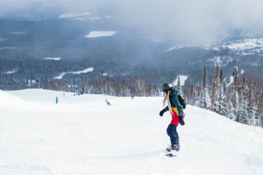 Kadın Snowboard karlı bir yamaçta rides.