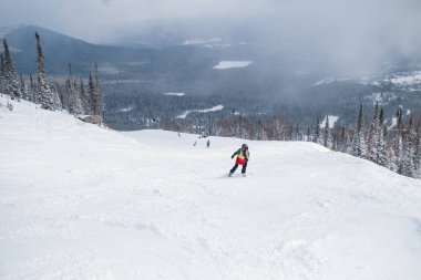 Karlı bir yamaçta bir snowboard snowboard freerider rides.