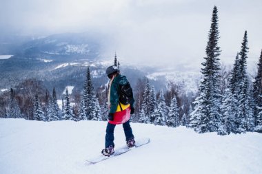 Dağlarda karlı bir yamaçta Snowboarder emrindeki hürsüvari sürmek.