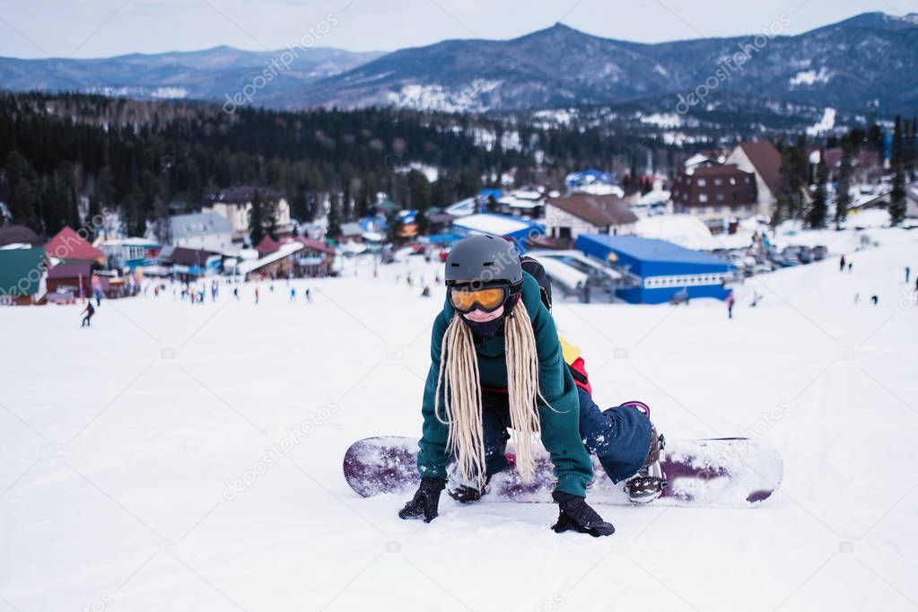 Woman snowboarder learns to ride in the mountains on a snowy slope.
