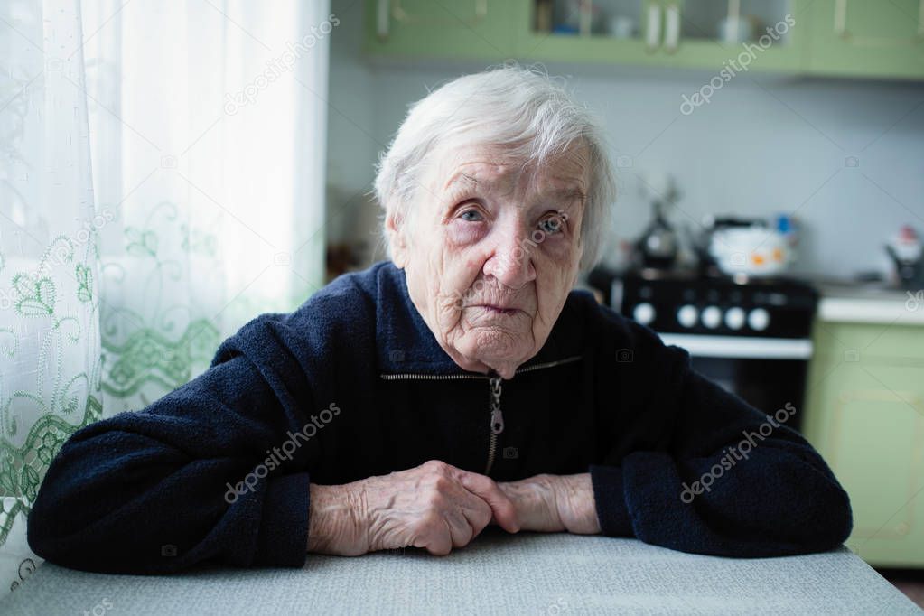 An elderly woman portrait near window in the house.