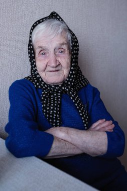 Kafasında atkı olan yaşlı bir kadının portresi.