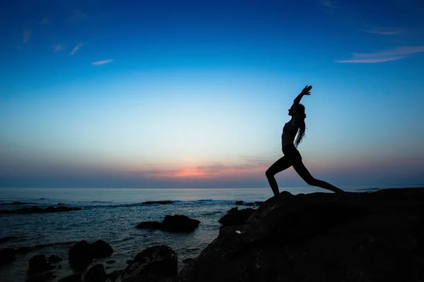 瑜伽女人在海洋海滩上做运动在惊人的暮色中剪影 — 图库照片