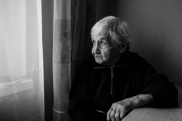 Evinde Yaşlı Bir Kadın Özlemle Pencereden Dışarı Bakar Yaşlı Kadın — Stok fotoğraf