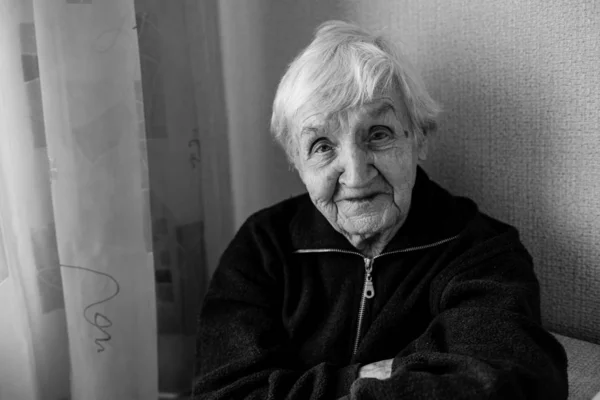 Black and white portrait of an old woman in his house. Care for lonely elderly.