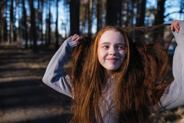 可爱的女学生与长红头发摆姿势的相机在松树公园在夏天 — 图库照片