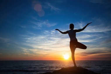 Siluet genç meditasyon kadın inanılmaz gün batımında okyanus plajda yoga pratik. 