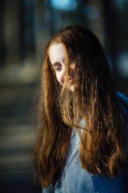 Kızıl saçlı küçük kız Park'ta bir portre için poz.