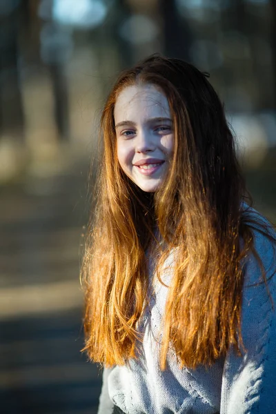 Kızıl saçlı küçük kız Park'ta bir portre için poz.