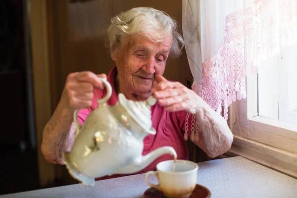 一位退休的老太太在厨房里喝茶 — 图库照片