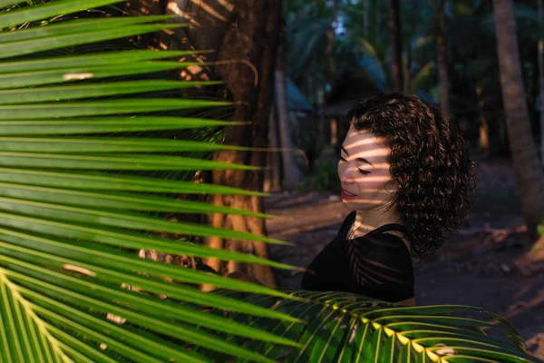 ヤシの木の葉の間の混合人種の若い女性の肖像 — ストック写真