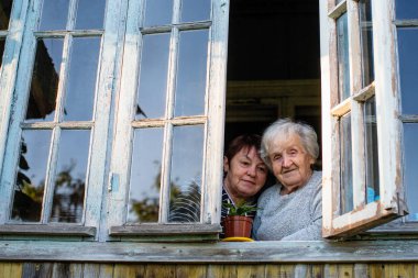 Yaşlı kadın ve köy evinin penceresinde onun yetişkin kızı.