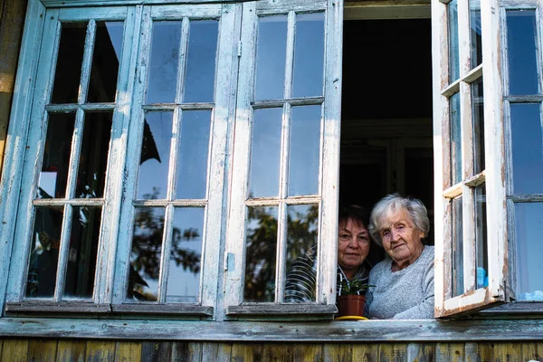 Stará Babička Její Dospělá Dcera Okně Vesnického Domu — Stock fotografie
