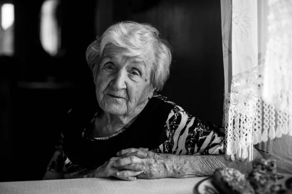 坐在桌旁的老妇人在他家的厨房里 — 图库照片
