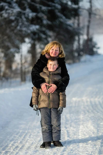 雪に覆われた冬の公園で男の子と遊ぶ若い女性 — ストック写真