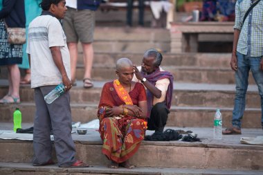 Varanasi, Hindistan - 23 Mar 2018: Kuaför hacıların saçlarını kesiyor. Varanasi'de bir saç kesimi Hinduizm'de arınma ritüeli olarak kabul edilir. Efsanelere göre, şehir 5000 yıl önce Tanrı Shiva tarafından kurulmuştur..