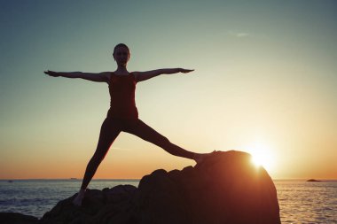 Yoga yapan kadın sabah egzersizlerini şafakta deniz kenarında yapıyor.. 