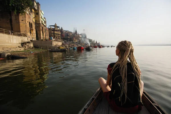 Tourist woman on a boat glides through the water on the Ganges river, Varanasi, India.