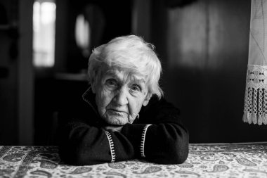 Yalnız üzgün yaşlı bir kadının siyah beyaz portresi.