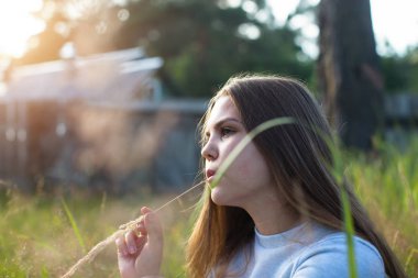 Güzel kız yaz kırsal yeşil çim oturan. 