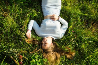 Yazın yeşil çimenlerde yatan güzel bir kız. Yukarıdan fotoğraf görünümü.
