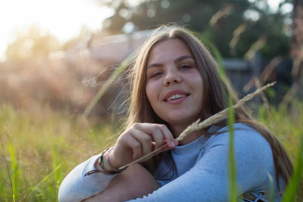 夏の田舎の緑の草に座っているかわいい女の子 — ストック写真