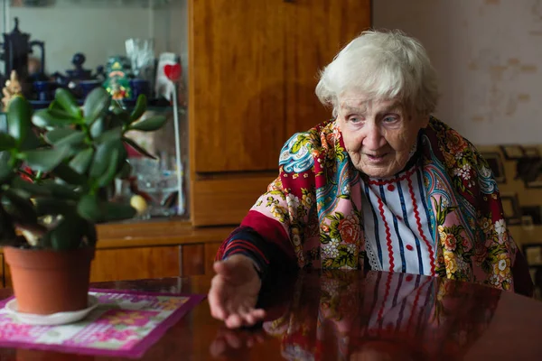 Starsza Kobieta Jasnych Ubrań Gesty Siedzi Przy Stole — Zdjęcie stockowe