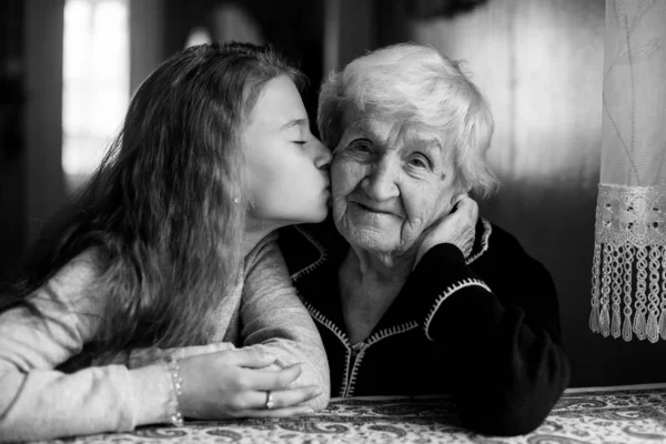 A little girl kisses her happy grandmother. Black and white photo