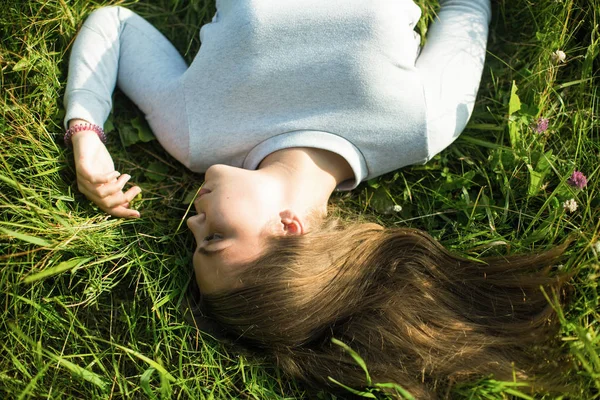 緑の草の上に横たわっている若い女の子のトップビューの画像 — ストック写真