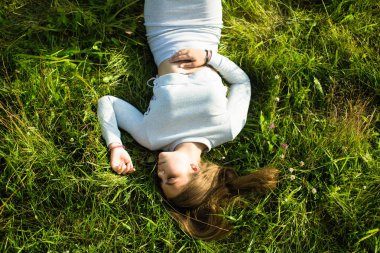 Yeşil çim yatarken genç bir kızın üst resmi.