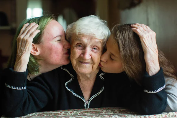 Две Внучки Целуют Щеки Старой Бабушки — стоковое фото