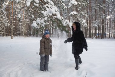 Karlı bir kış Parkı'nda oğluyla oynayan genç kadın.