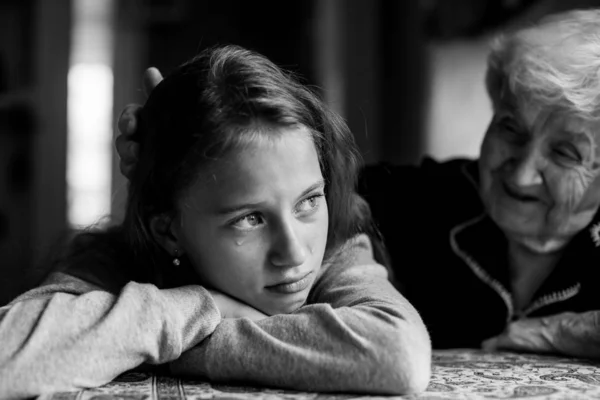 Little girl cries and her grandmother soothes stroking his hand on the head. Black and white photo.