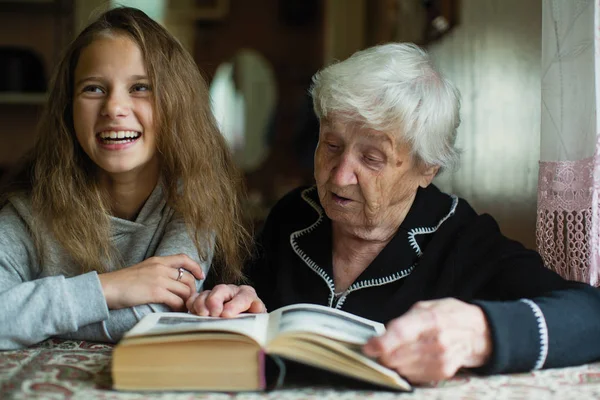 可爱的小女孩与她的老曾祖母读一本书 — 图库照片