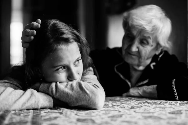 Grandma stroking the head crying granddaughter. Black and white photo.